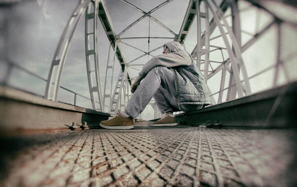 lonely and anxious man sitting on a bridge